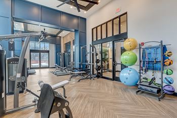 A gym with cardio equipment and weights on the floor and glass doors